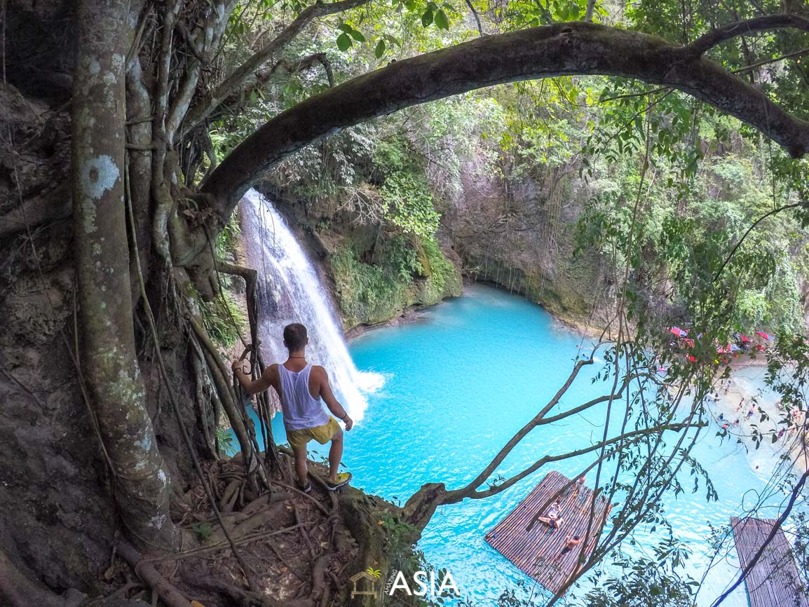 mężczyzna podziwiający niebieski wodospad w dżungli